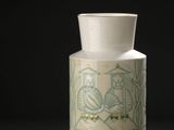 un vase blanc orné d'un motif vert