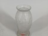a glass vase with a bird on it on a white surface