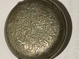 a silver pocket watch on a white surface