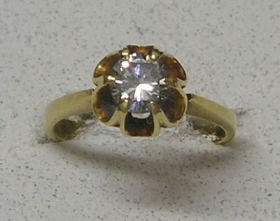 une bague en or sertie d'un diamant, posée sur une table