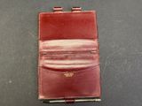 a red leather wallet with a pen in it sitting on a table