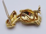 a gold brooch with a pair of scissors in it