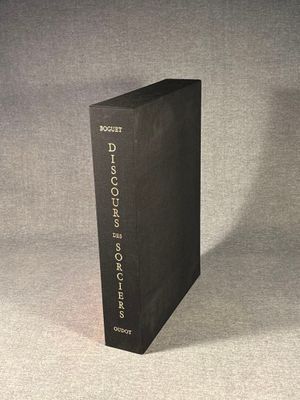 a black book sitting on top of a table next to a white wall