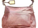 the brown leather purse is sitting on a white surface