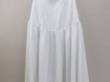 a white dress hanging on a hanger against a wall
