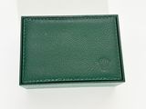 une photo d'un portefeuille en cuir vert posé sur une surface blanche