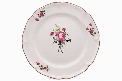 EST Assiette en faïence émaillée polychrome à décor floral.