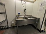 a stainless steel sink in the corner of a room
