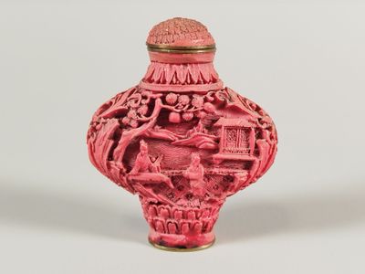 un vase rouge orné d'un motif sur un fond blanc