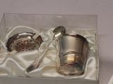 a silver cup and spoon in a box on a table