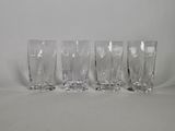 four clear glasses sitting next to each other on a white surface