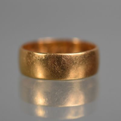 a close up of a gold wedding ring on a reflective surface