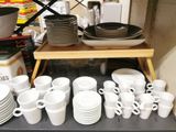 many cups and saucers on a shelf in the kitchen