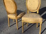 pair of antique french style chairs in the middle of a parking lot