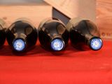 four bottles of wine are lined up on a red table