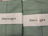 two green pillows with white labels on them sitting on a bed