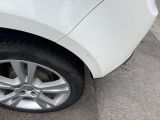 a cat sitting on the wheel of a white car