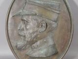 une médaille d'argent sur laquelle figure un homme coiffé d'un chapeau