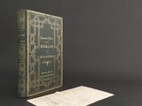 an old book sitting on a table next to a piece of paper