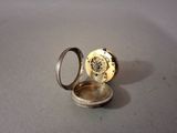 une montre de poche en argent posée sur une table à côté d'une bague