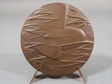 a brown plate with a bird on it on a stand
