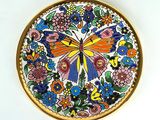 une assiette colorée ornée d'un papillon, posée sur un fond blanc