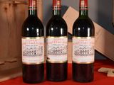 three bottles of wine sitting on a red table cloth