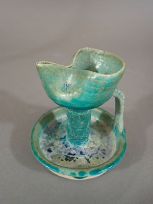 a blue and green cup and saucer sitting on a plate