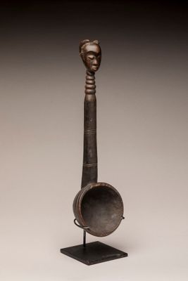 une sculpture en bronze représentant la tête d'une femme tenant une cuillère, posée sur un socle