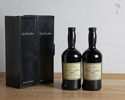 deux bouteilles de vin posées à côté d'une boîte noire sur une table
