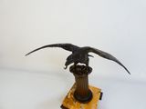 statue d'un aigle posée sur un socle, sur fond blanc