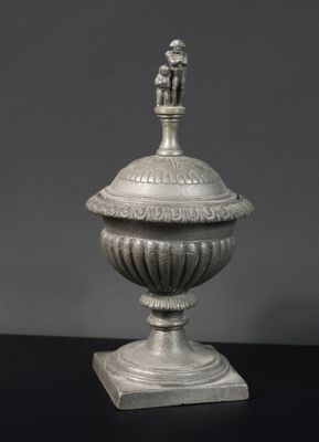 une urne en argent surmontée d'une figurine