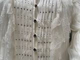 a mannequin wearing a white dress with black buttons on it