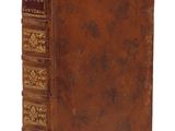 un vieux livre à la couverture brune posé sur une surface blanche