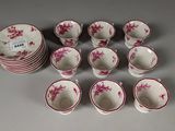 twelve cups and saucers with pink flowers on them sitting on a table