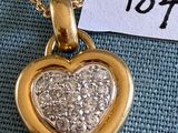 une photo d'un pendentif en or en forme de cœur, orné de diamants, suspendu à une chaîne