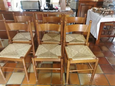 six chaises en bois disposées dans une pièce au sol carrelé