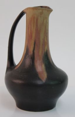 un vase brun et noir posé sur une surface blanche