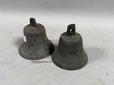 une paire de cloches anciennes posées sur un support blanc, accompagnées d'une étiquette