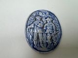 une petite assiette bleue et blanche sur laquelle est représenté un groupe de personnes