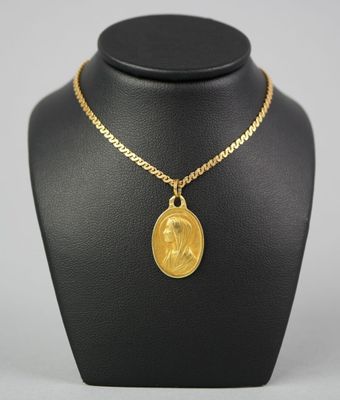 a gold necklace with a coin on a mannequin neck