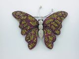 un gros plan d'une broche en forme de papillon posée sur une surface blanche