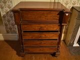 a wooden chest of drawers in the corner of a room