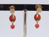 pair of red and gold earrings on a black stand