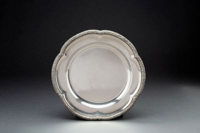 assiette en argent plaqué avec un bord perlé sur un fond gris