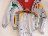 silver jacket with multicolored sleeves and a wooden hanger on a white wall