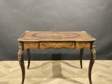 an old wooden table with a marble top on a wooden floor