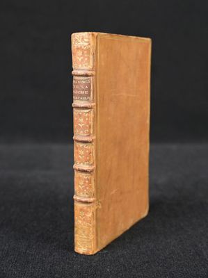 an old book sitting on top of a black cloth covered table