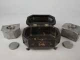 a small black box with coins in it on a white surface