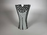 un vase noir et blanc posé sur une surface blanche